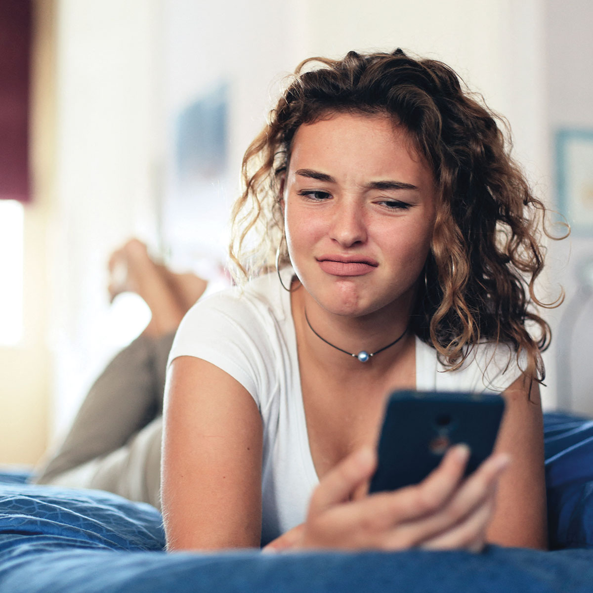 Photo of teen looking at their phone in mild disgust