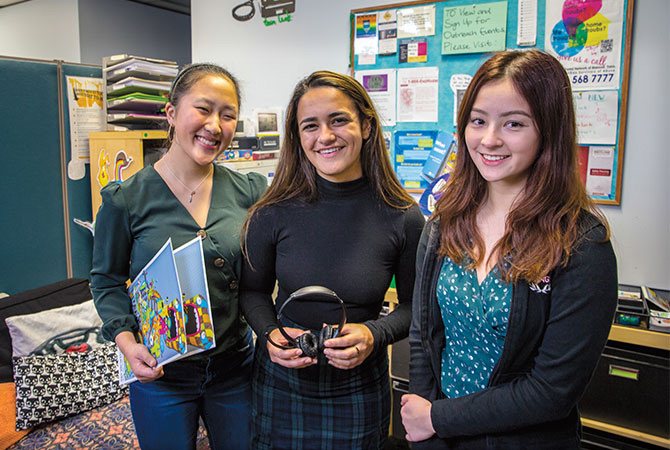 Three girls smiling in a classroom